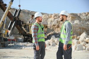 Portrait of stone quarry workers standing on the background of an excavator photo