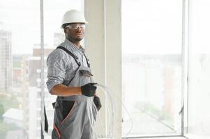 An African electrician stands on a construction site with a cable in his hands photo