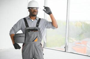 retrato de hermoso joven africano americano masculino constructor en difícil sombrero, trabajando a construcción sitio foto