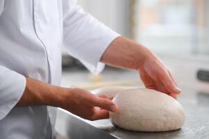 baker making bread , man hands , kneading a dough , cooking coat photo