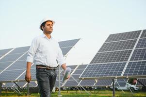 retrato de un joven indio masculino ingeniero o arquitecto a un solar panel granja. el concepto de limpiar energía foto