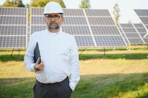 ingeniero hombre en casco en el campo de solar paneles foto