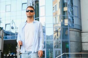 Young handsome blinded man walking with stick in town photo