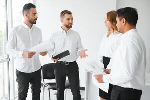 Happy businesspeople laughing while collaborating on a new project in an office. Group of diverse businesspeople working together in a modern workspace photo
