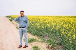 Young agronomist in rape field. Agribusiness concept. agricultural engineer standing in a rape field. photo