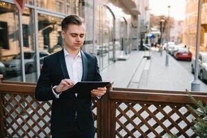 Young business man with tablet near of modern building. photo