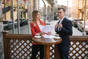 Preparation for meeting. Two young business people standing outside on the city street holding documents looking at each other smiling happy bottom view close-up. photo