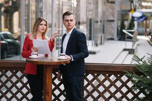 Preparation for meeting. Two young business people standing outside on the city street holding documents looking at each other smiling happy bottom view close-up photo