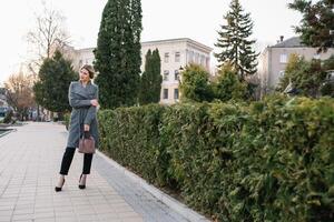 retrato de negocio mujer en sensación de concentrado estrés y ver estar y sostener el papel archivo sábana en el al aire libre peatonal caminar camino con el ciudad espacio de exterior moderno fachada edificio. foto