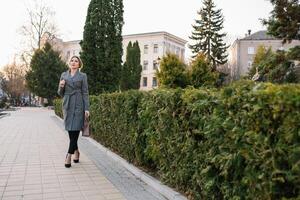 retrato de negocio mujer en sensación de concentrado estrés y ver estar y sostener el papel archivo sábana en el al aire libre peatonal caminar camino con el ciudad espacio de exterior moderno fachada edificio foto