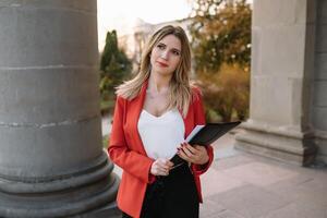 retrato de negocio mujer en sensación de concentrado estrés y ver estar y sostener el papel archivo sábana en el al aire libre peatonal caminar camino con el ciudad espacio de exterior moderno fachada edificio foto