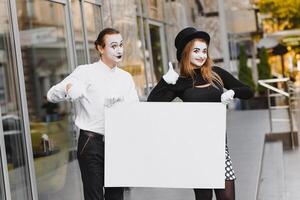 Your text here. Actors mimes holding empty white letter. Colorful portrait with gray background. April fools day photo