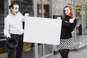 Your text here. Actors mimes holding empty white letter. Colorful portrait with gray background. April fools day photo