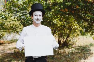 Your text here. Actors mimes holding empty white letter. Colorful portrait with green background. April fools day photo