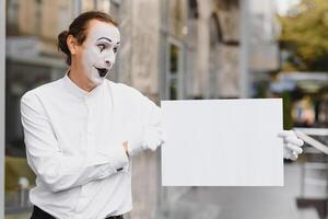 Your text here. Actor mime holding empty white letter. Colorful portrait with gray background. April fools day photo