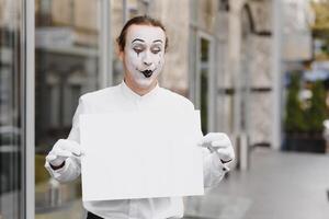 Your text here. Actor mime holding empty white letter. Colorful portrait with gray background. April fools day photo