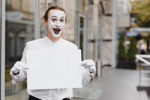 Your text here. Actor mime holding empty white letter. Colorful portrait with gray background. April fools day photo