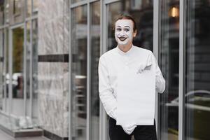 Your text here. Actor mime holding empty white letter. Colorful portrait with gray background. April fools day photo
