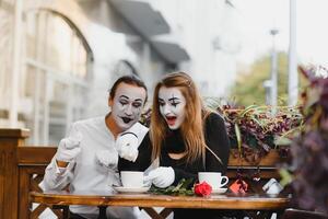 mime guy and girl in cafe drinking coffee. Mime in front of Paris cafe acting like drinking tea or coffee. photo