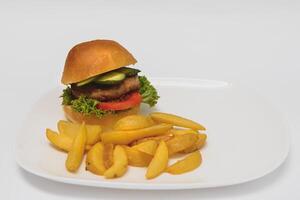 tasty hamburger, French fries and chili sauce on white plate, Fast food with copy space photo