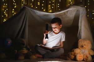 the child is reading a book with a flashlight photo