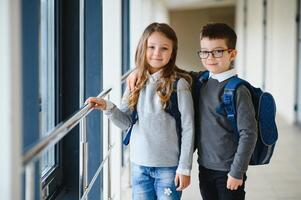 Portrait of smiling school kids in school corridor with books photo