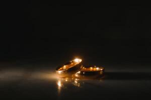 Elegant wedding rings for the bride and groom on a black background with highlights, macro, selective focus. photo