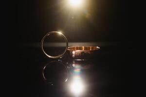 Elegant wedding rings for the bride and groom on a black background with highlights, macro, selective focus. photo