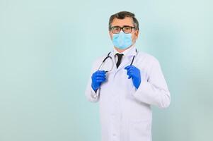 Man in medical gloves putting on protective face mask against blue background. photo
