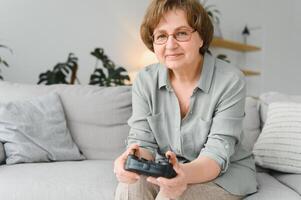 Older person having fun playing a console with a game sitting on the sofa. photo