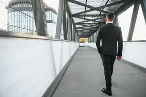 Stockbroker near the office. A successful and advanced handsome business man in a suit looks up in front of him standing on the background of concrete steps. photo
