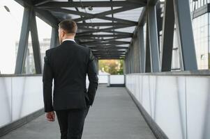 Stockbroker near the office. A successful and advanced handsome business man in a suit looks up in front of him standing on the background of concrete steps. photo