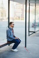 Blinded man waiting for bus at a bus station photo