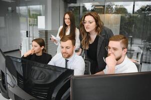 Smiling business people sitting at a desk in front of a laptop computer photo