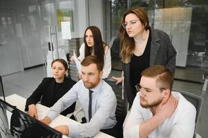 Smiling business people sitting at a desk in front of a laptop computer photo