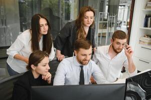 Smiling business people sitting at a desk in front of a laptop computer photo
