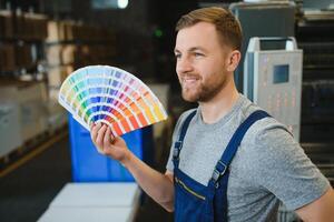 Man working in printing house with paper and paints photo