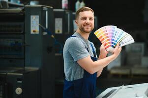 Man working in printing house with paper and paints photo