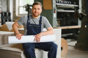 Man working in printing house with paper and paints photo