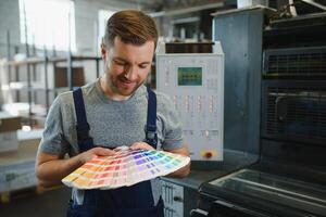 Portrait of worker at control room checking print quality at printing house. photo