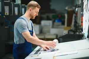 Man worker measuring printing color with spectrometer on the operating desk of the printing plant photo