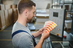 Man working in printing house with paper and paints photo