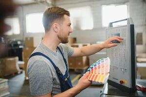 Man working in printing house with paper and paints photo