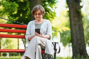 An elderly woman sitting on bench in summer park photo