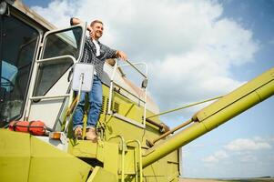 Harvester machine driver climbing into a cab to harvest his wheat field. Farmer getting in combine on ladder holding railing. Agronomist. Rancher after harvesting work photo