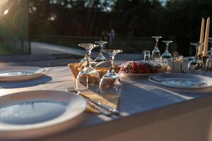 empty wine glasses on banquet served table in open air in rays of setting sun photo