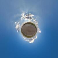 simple little tiny planet without buildings in blue sky with beautiful clouds. Transformation of spherical panorama 360 degrees. Spherical abstract aerial view. Curvature of space. photo
