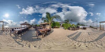 360 hdri panorama with coconut trees on ocean coast near tropical shack or open cafe on beach with swing in equirectangular spherical seamless projection photo