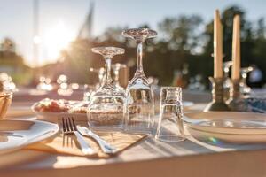 empty wine glasses on banquet served table in open air in rays of setting sun photo