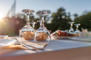 empty wine glasses on banquet served table in open air in rays of setting sun photo